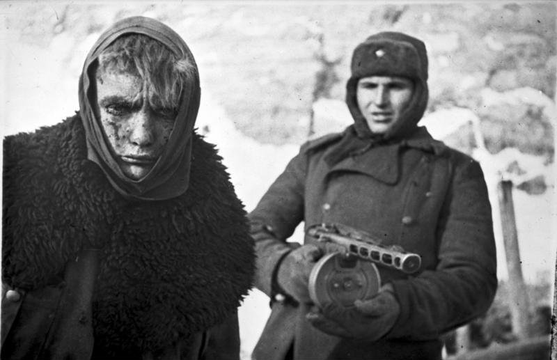 A Red Army soldier marches a German soldier into captivity.